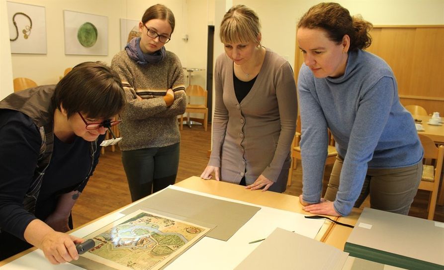 Die Papierrestauratorin Jutta Keddies M.A., FSJ-lerin Nele Stelljes, Kunstwissenschaftlerin Karina Zubkowski M.A. und Museumsleiterin Ellen Horstrup M.A. (v.l.n.r.) betrachten einen Kupferstich mit dem Licht einer Speziallampe.  Foto: eb