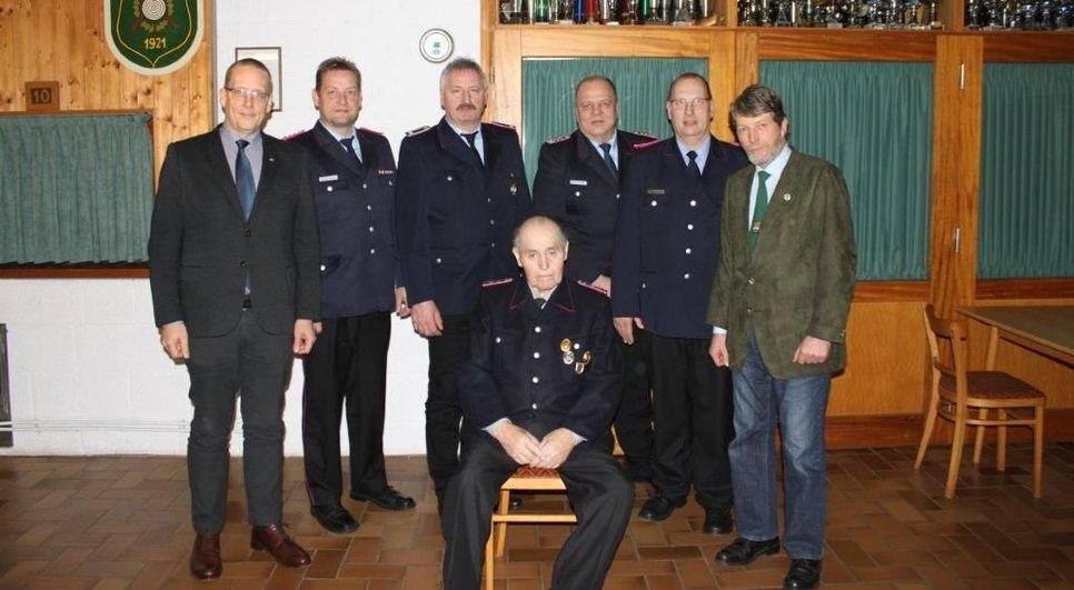 Geehrte Mitglieder mit Führungspersonal (v.l.): Stellvertretender Samtgemeindebürgermeister Marco Noetzelmann, GBM Stephan Beushausen, Bernd von Glahn, stellvertretender amtierender OBM Günter Meyer, OBM Wilhelm Bösch, Bürgermeister Johann König. Sitzend: Adolf Lis (geehrt für 70 Jahre Mitgliedschaft). Foto: Feuerwehr Heinschenwalde