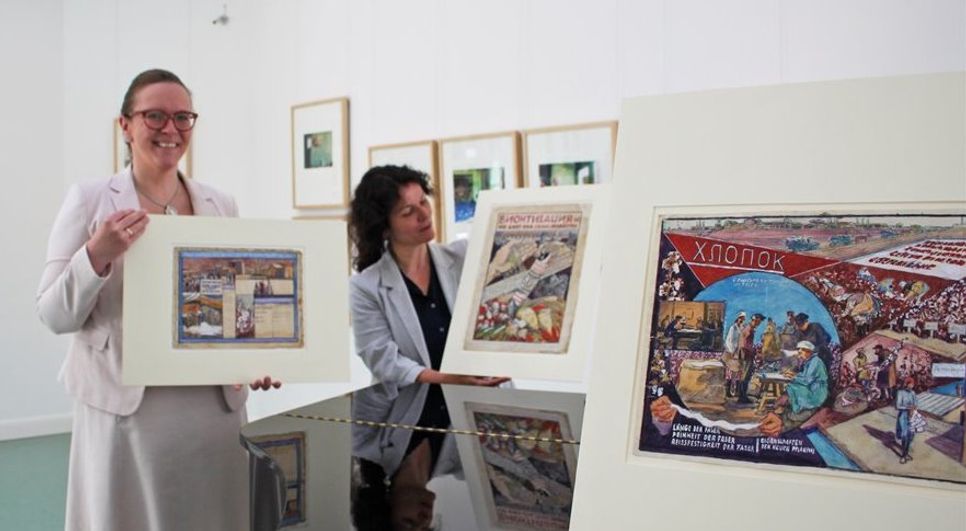 Corinna Facktor von der Fielmann Filiale aus Osterholz-Scharmbeck und Beate Arnold vom Barkenhoff präsentierenn die Plakatenwürfe Heinrich Vogelers aus den 1930er Jahren.   Foto: pvio