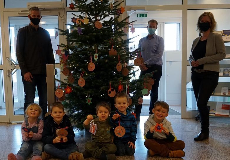 Kinder der Kita „Drachenhöhle“ Frelsdorf schmückten mit Bürgermeister Guido Dieckmann ( Mitte) den Wunschweihnachtsbaum. Für die Organisation ist Mitarbeiter Kai Wilkens (Innerer Service) auf dem Foto links zuständig. Claudia Lühmann (Erste Gemeinderätin) staunte nicht schlecht, was die Kleinen da mitgebracht hatten.   Foto: khe