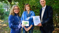 Dr. Maren Meyer-Grünefeldt (v. li.) und Bettina Schroeder freuen sich über das von Karsten Behr überreichte „NATURbegeistert“-Schild.