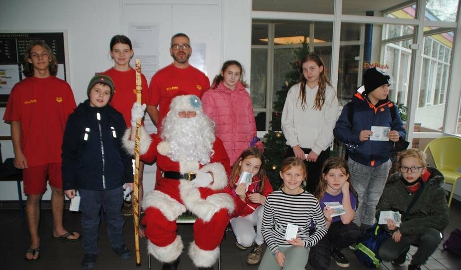 Die Ausbilder Helge Borgward, Louise und Erik Oudemast (hinten v.l.) freuen sich mit den neuen Junior-Retter:innen über den Besuch des Weihnachtsmannes beim letzten Training vor der Winterpause.