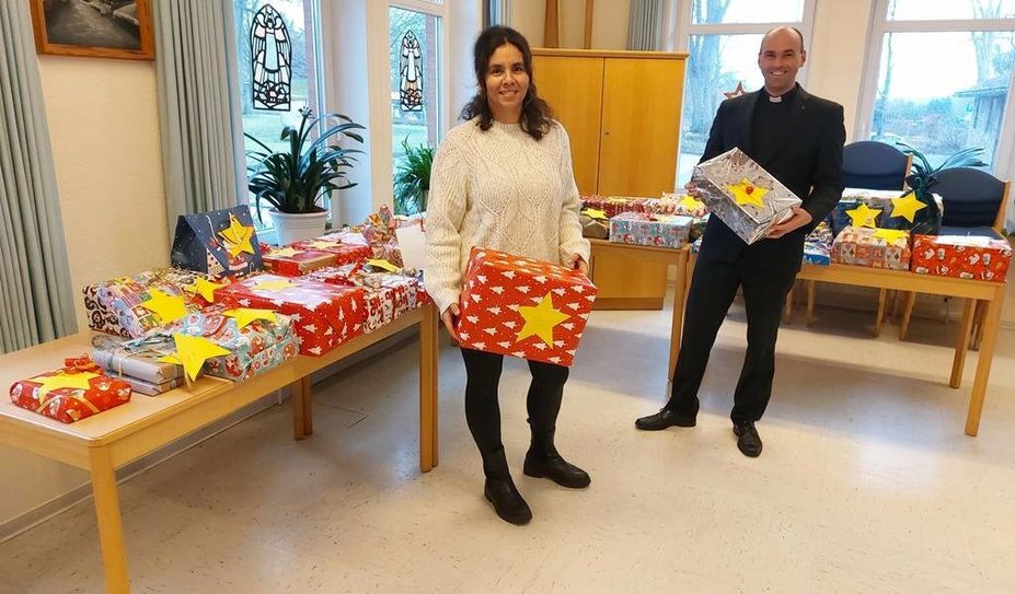 Melanie Blank und Pastor Florian von Issendorff vor den Geschenken, bevor sie unter dem Weihnachtsbaum von 51 Kindern in der Gemeinde landen.